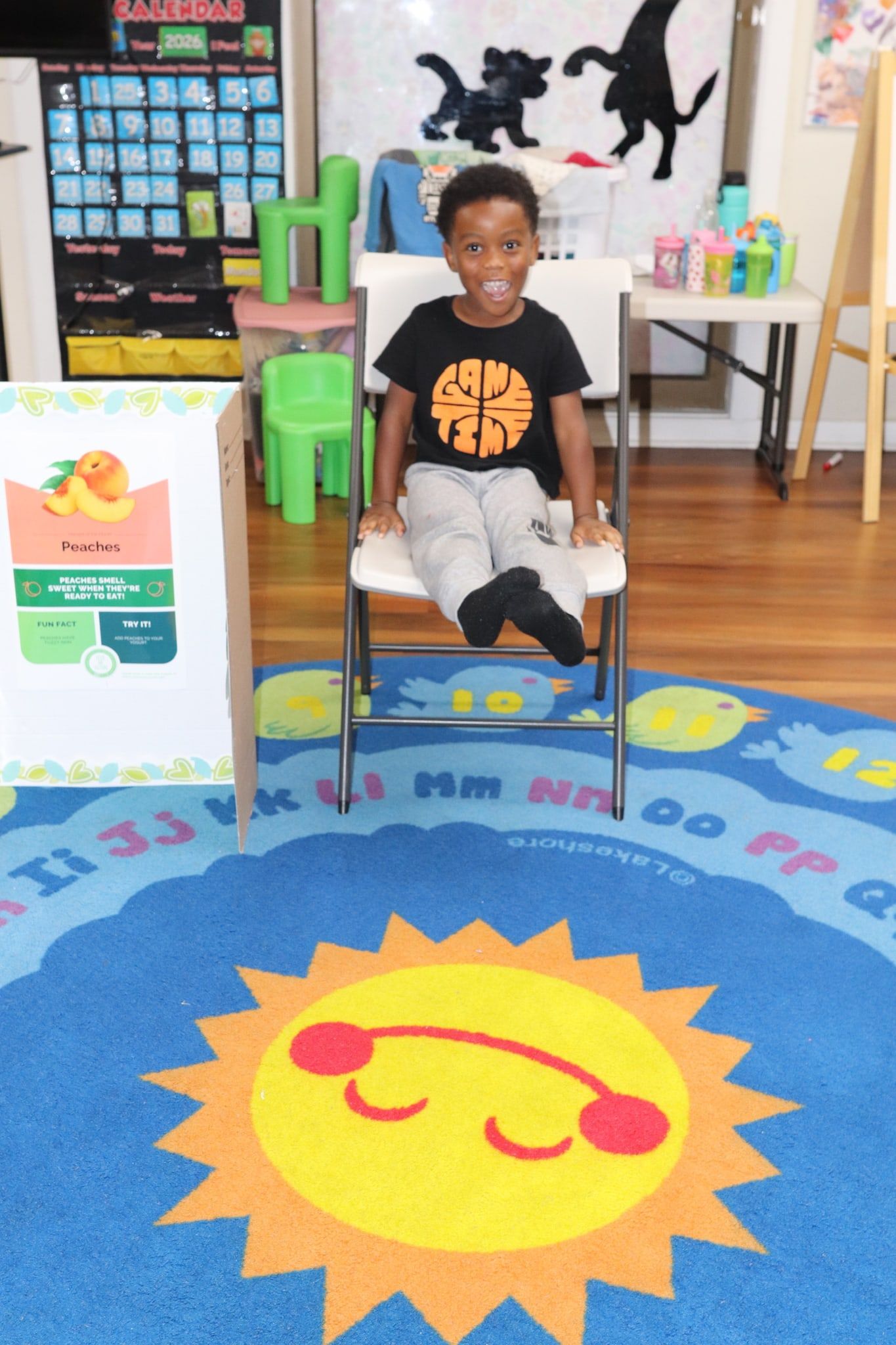 A smiling boy sitting on a chair on the sun rug