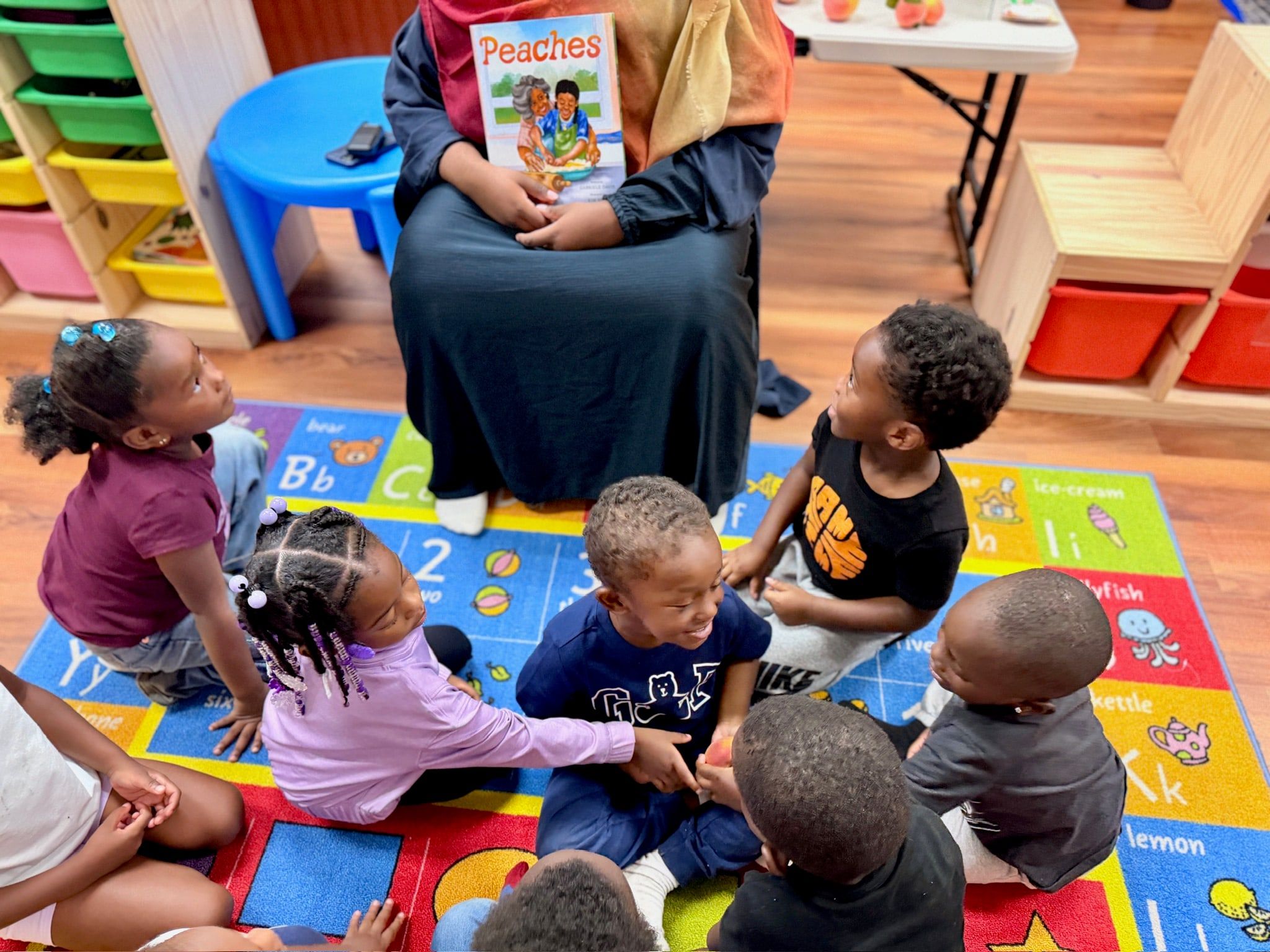 Children on the alphabet rug listening to a story