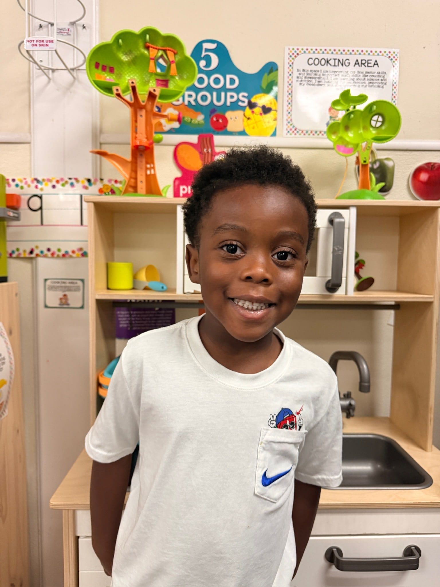 A smiling boy in the play kitchen corner
