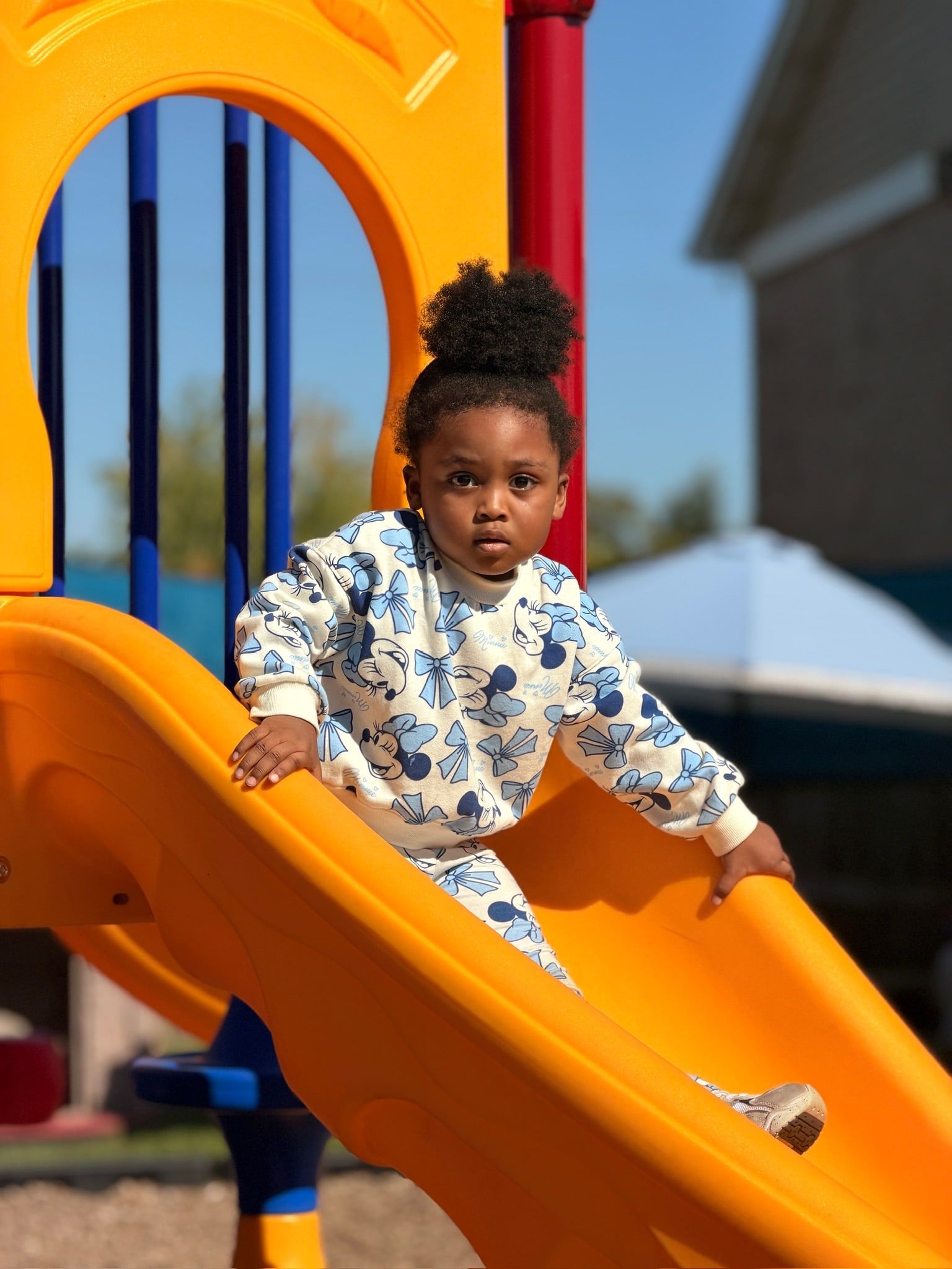 A toddler at the top of the yellow slide